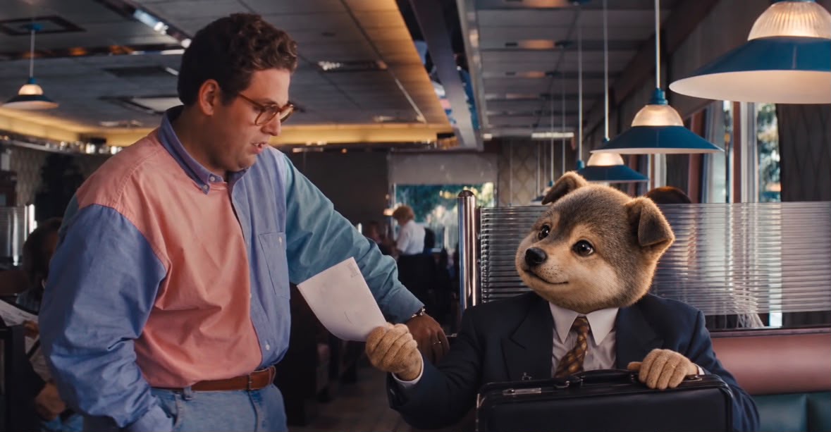 The Wolf mascot handing over a document with a briefcase on the table