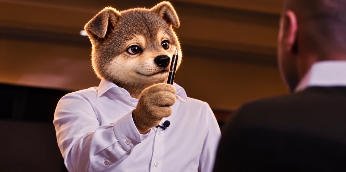 The Wolf mascot in a white shirt holding a pen, facing a broker